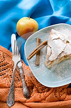 A piece of apple pie lying on blue plate, apple, cinnamon sticks