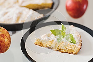 Piece of apple pie served with icing sugar and fresh mint
