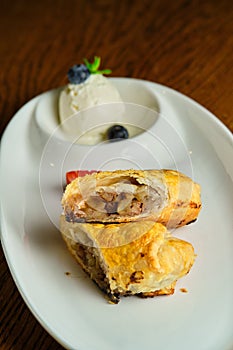 A piece of apple strudel with vanilla ice cream and strawberries