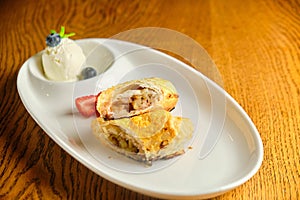 A piece of apple strudel with vanilla ice cream and strawberries