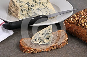 Piece of Auvergne blue cheese on a slice of seeded bread with a knife close-up