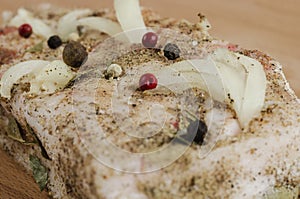 A piece of bacon with different types of pepper and salt on the board