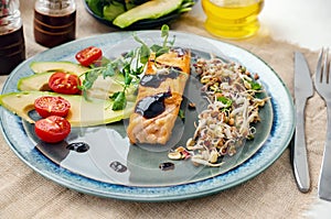 A piece of baked red fish with a side dish of sprouts and avocado salad. Macrobiotic food concept. Healthy food