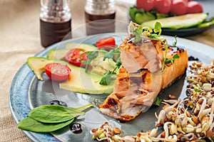 A piece of baked red fish with a side dish of sprouts and avocado salad. Macrobiotic food concept. Healthy food