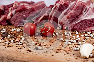 A piece of beef with tomatoes, grlic and pepper on the wooden board