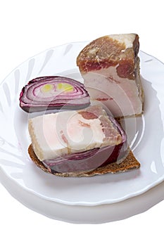 Piece of brackish bacon on rye bread and a red onion