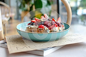 Piece of bread fried in eggs with fruits on top. Figs, raspberries, strawberries, mint,  blueberry fruits on toast