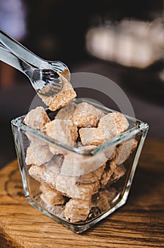 A piece of brown sugar in small confectionery tweezers.