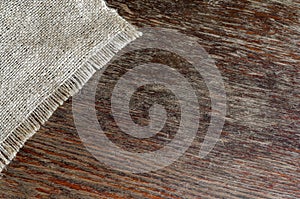 A piece of burlap cloth on an old scratched wooden background