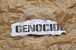 Piece of burnt card with word Genocide on crumpled paper, top view