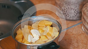 Piece of Butter Falls into the Potatoes in a Saucepan on the Home Kitchen