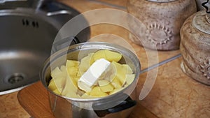 Piece of Butter Falls into the Potatoes in a Saucepan on the Home Kitchen. Slow Motion