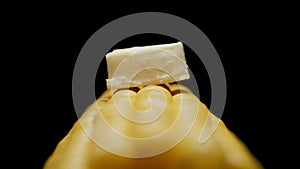 Piece of butter on sweetcorn cob on a black background. Close up.