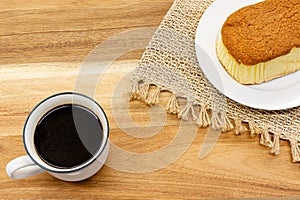 Piece of cake and black coffee on wooden table in cafe ,top view.