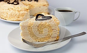 A piece of cake Napoleon and a cup of aromatic coffee in the background. Close-up. Selective focus