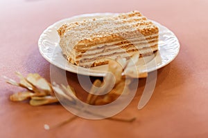 Piece of cake Napoleon on white plate decorated with dried twigs