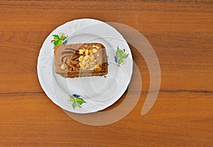 Piece of cake with nuts on plate on wooden table