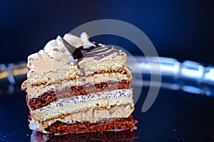 A piece of cake with oil cream stands on a metal tray. The photo is slightly blurred