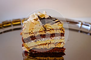 A piece of cake with oil cream stands on a metal tray. The photo is slightly blurred