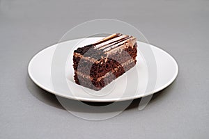 Piece of cake or pastry in white plate on grey background