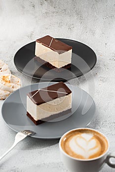 Piece of cake with souffle Bird`s milk , biscuit, mousse and dark chocolate on a dark plate, white souffle cake. Menu