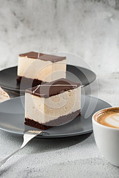 Piece of cake with souffle Bird`s milk , biscuit, mousse and dark chocolate on a dark plate, white souffle cake. Menu