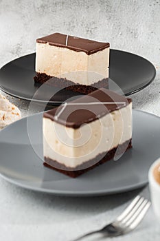 Piece of cake with souffle Bird`s milk , biscuit, mousse and dark chocolate on a dark plate, white souffle cake. Menu