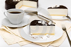 Piece of cake with souffle `Bird`s milk`, biscuit, mousse and dark chocolate on a white plate