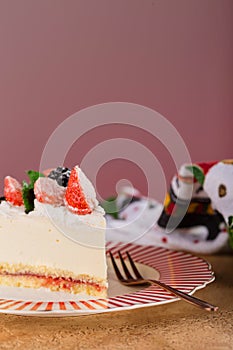 Piece of cake with strawberries, blackberries and mint on a beautiful festive plate.