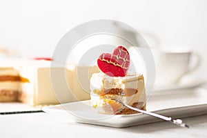 A piece of cake on a white plate and a light background. Dessert for Mother`s Day