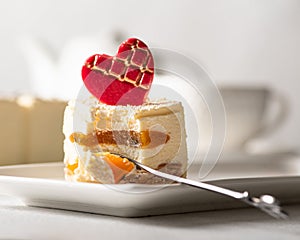 A piece of cake on a white plate and a light background. Dessert for Mother`s Day