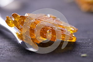 Piece of cannabis oil concentrate aka shatter with dabbing tool