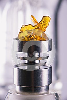 Piece of cannabis oil concentrate aka shatter over a titanium ri