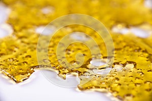 A piece of cannabis oil concentrate aka shatter on whit