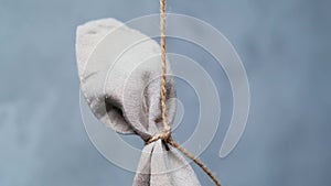 piece of canvas fabric is suspended by rope and hangs against gray-blue background. Abstraction, thoughts of author. bag