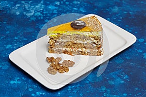 Piece of carrot cake with icing and walnut on plate