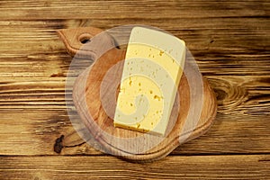 Piece of cheese on cutting board on wooden table