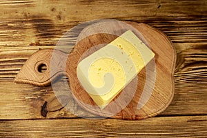 Piece of cheese on cutting board on wooden table