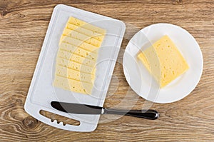 Piece of cheese in plate, slices on cutting board, knife