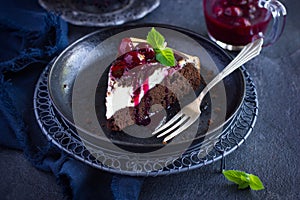 Piece of cheesecake brownie cake with cherry sauce