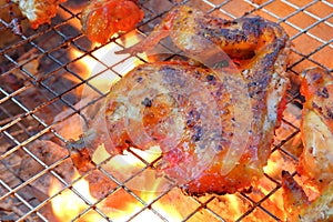 Piece of chicken thigh over on Barbecue grill with fire.