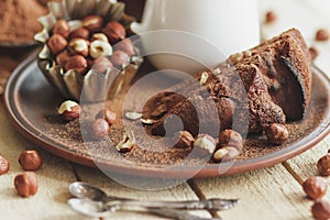 Piece of chocolate cake, hazelnuts and jar with milk