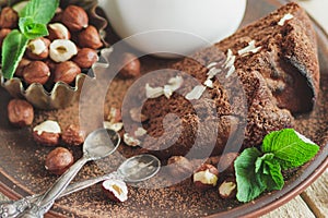 Piece of chocolate cake, mint leaves, hazelnuts and jar with milk