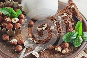 Piece of chocolate cake, mint leaves, hazelnuts, and jar with milk