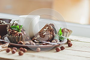 Piece of chocolate cake, mint leaves, hazelnuts and jar with milk
