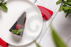 Piece of chocolate Mozart cake on white plate on wooden table