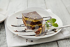 Piece of chocolate three-layer cake and miny on a white plate in a cafe