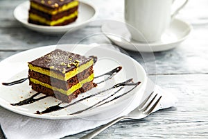 Piece of chocolate three-layer cake on a white plate in a cafe