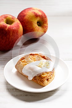 Piece of cinnamon apple pie on a white plate with fresh apple in background, autumn food concept