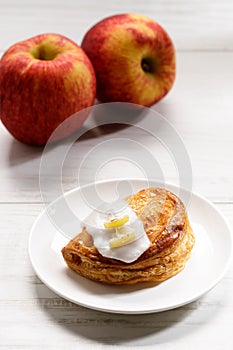 Piece of cinnamon apple pie on a white plate with fresh apple in background, autumn food concept